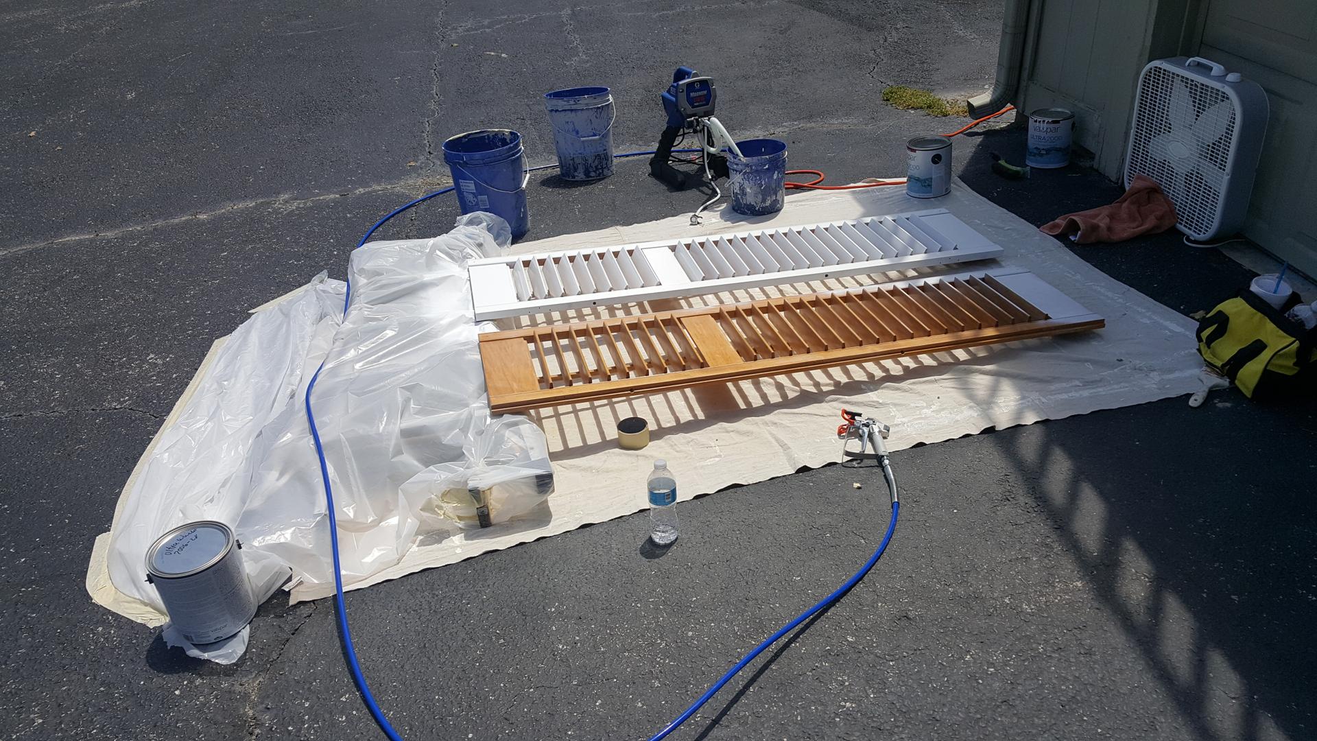 Wood shutters being spray painted white during a refinishing job